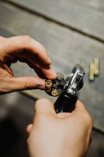 person reloading revolver with centerfire cartridges